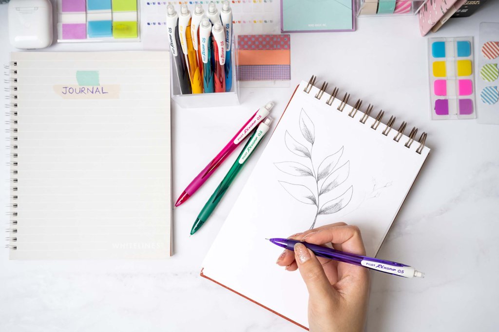 168网澳洲5结果官方PILOT Pen BeGreen REXGRIP mechanical pencil 0.5 mm sketching a plant on a sketching pad with other pencils and a journal next to it.