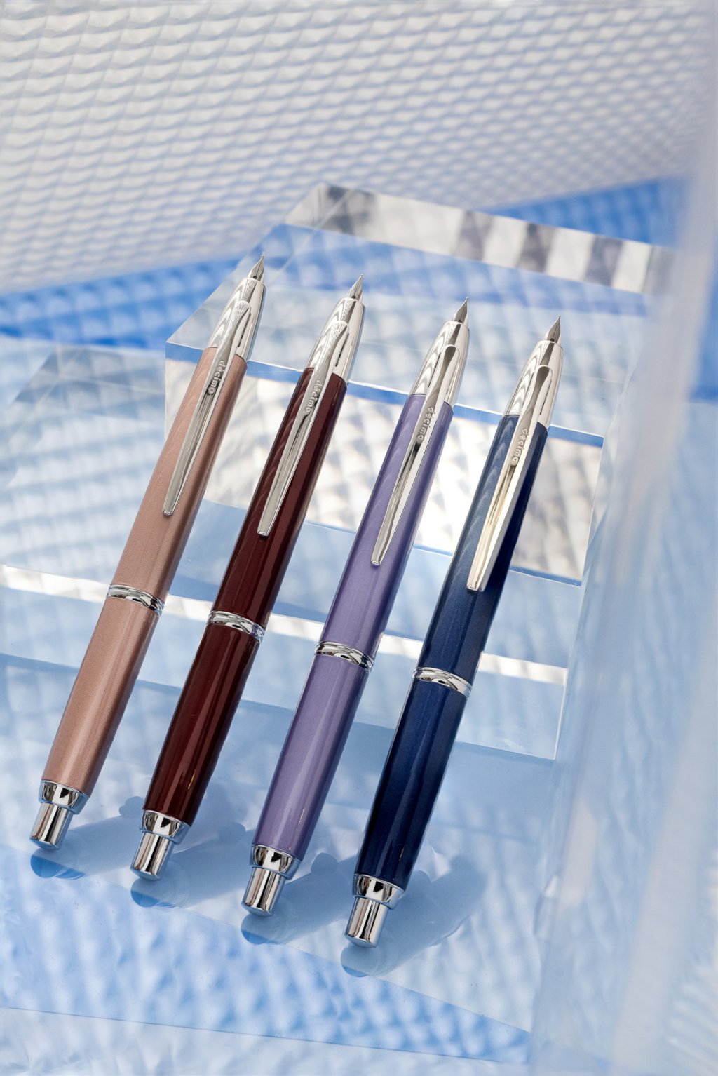 168网澳洲5结果官方PILOT Capless Decimo Retractable Fountain Pens, also known as Vanishing Points, lined up on a clear block. There are four different coloured barrels: Champagne Pink, Red, Violet and Dark Blue.